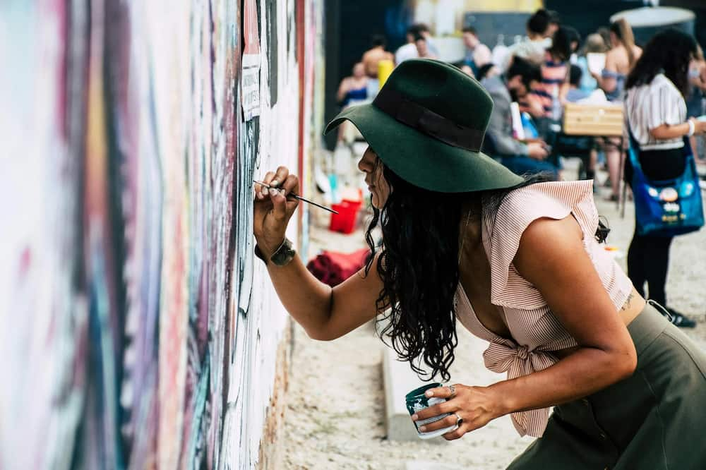 woman painting graffiti on wall - graffiti vs vandalism